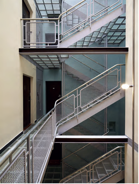 Innenansicht eines mehrstöckigen Treppenhauses mit Metallgeländern und Flurtüren, Corbusier